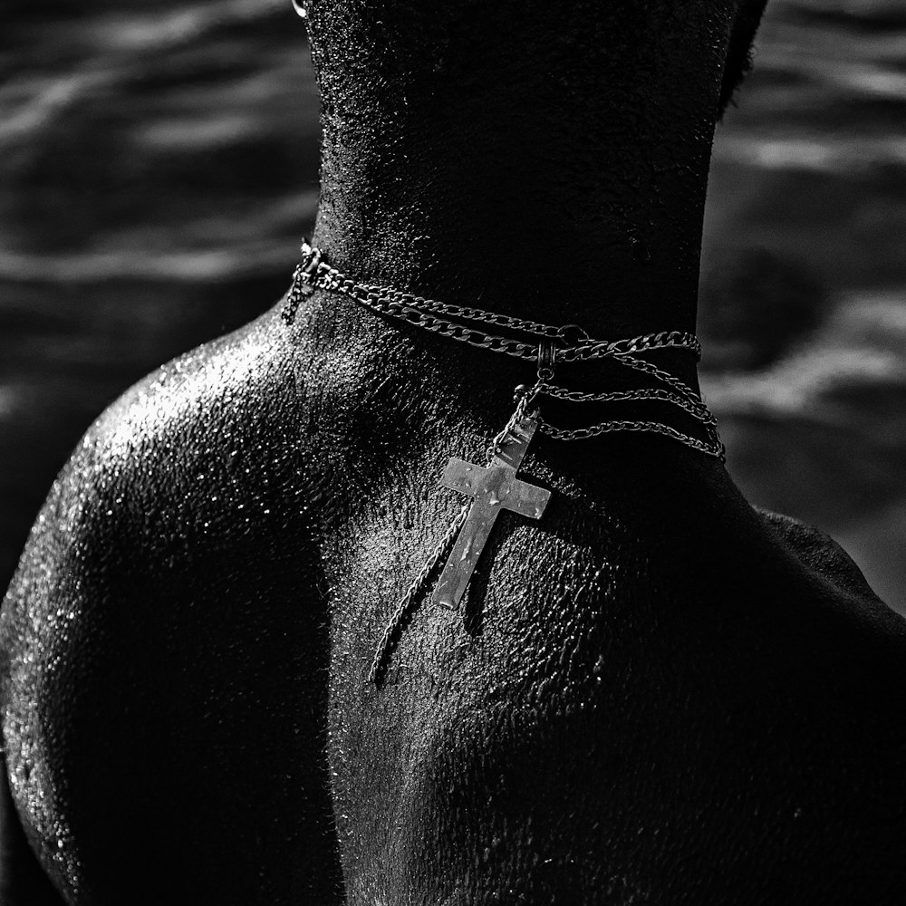 a black and white photo of a cross on a chain