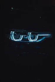 Close-up of high-quality car LED lights glowing bright blue neon in a dark garage.