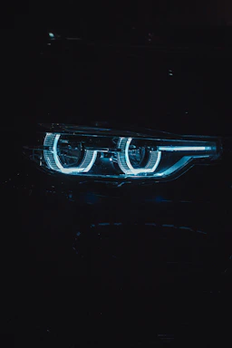 Close-up of a sleek Plaser LED bulb glowing with green and white light inside a car headlight.