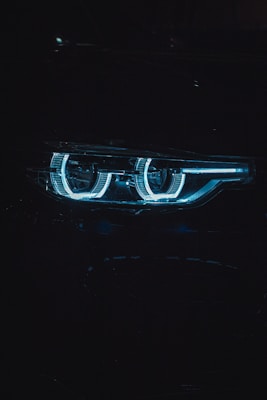 Set of used car headlights glowing softly with a blue tint.