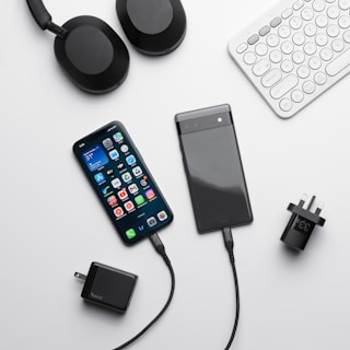 a cell phone, headphones, a keyboard, and a charger on a