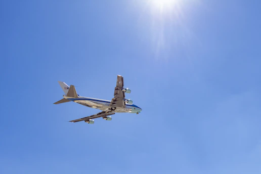 A sleek airplane taking off against a clear blue sky with golden sunlight.