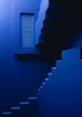 a blue staircase leading to a window in a building