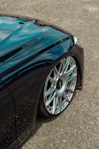Side view of a car fitted with shiny Volparesil wheels on a city street.