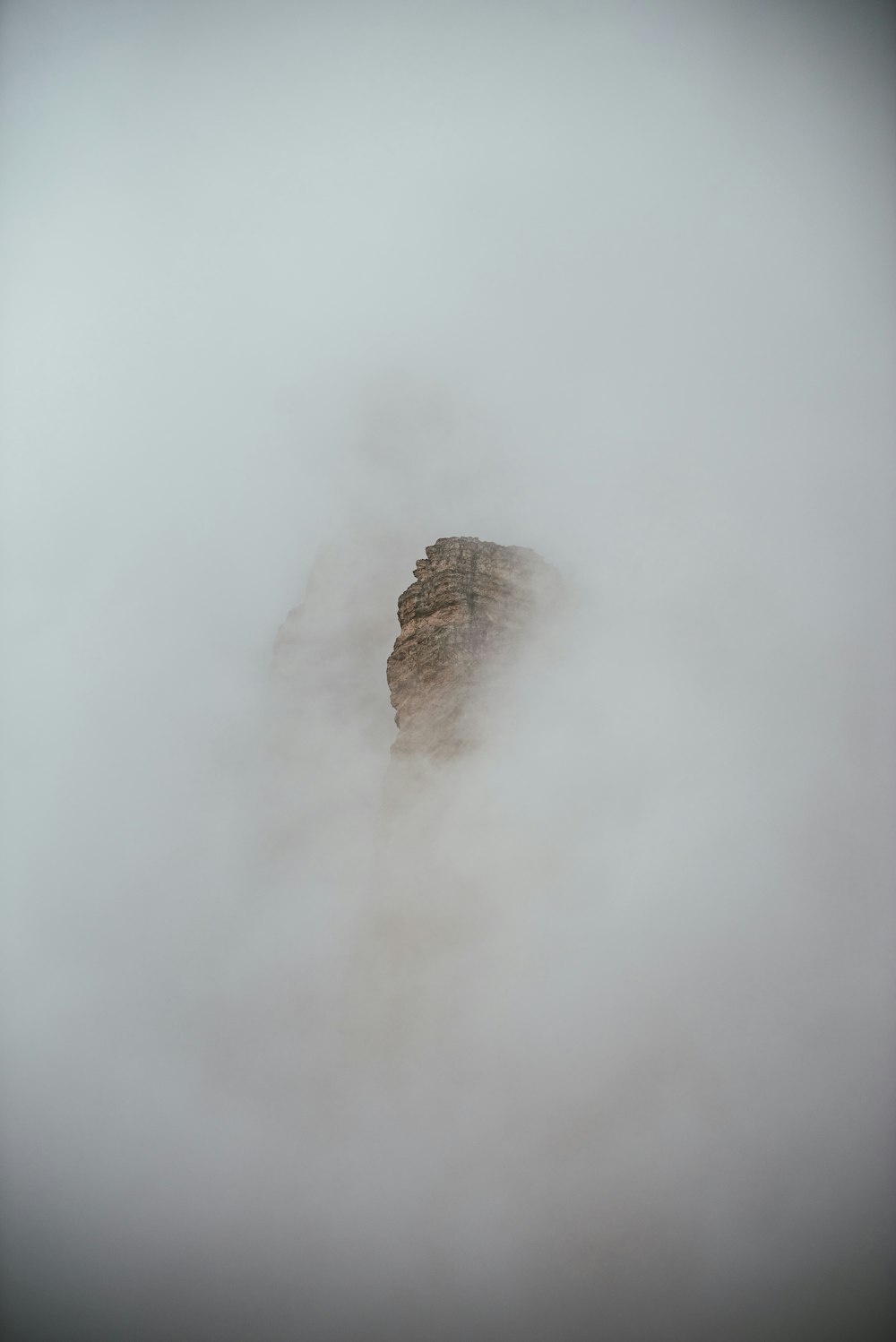 a rock in the middle of a foggy mountain