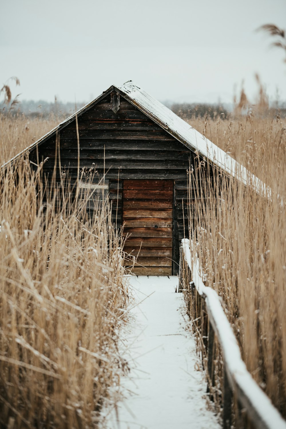 an old barn in the middle of a snowy field