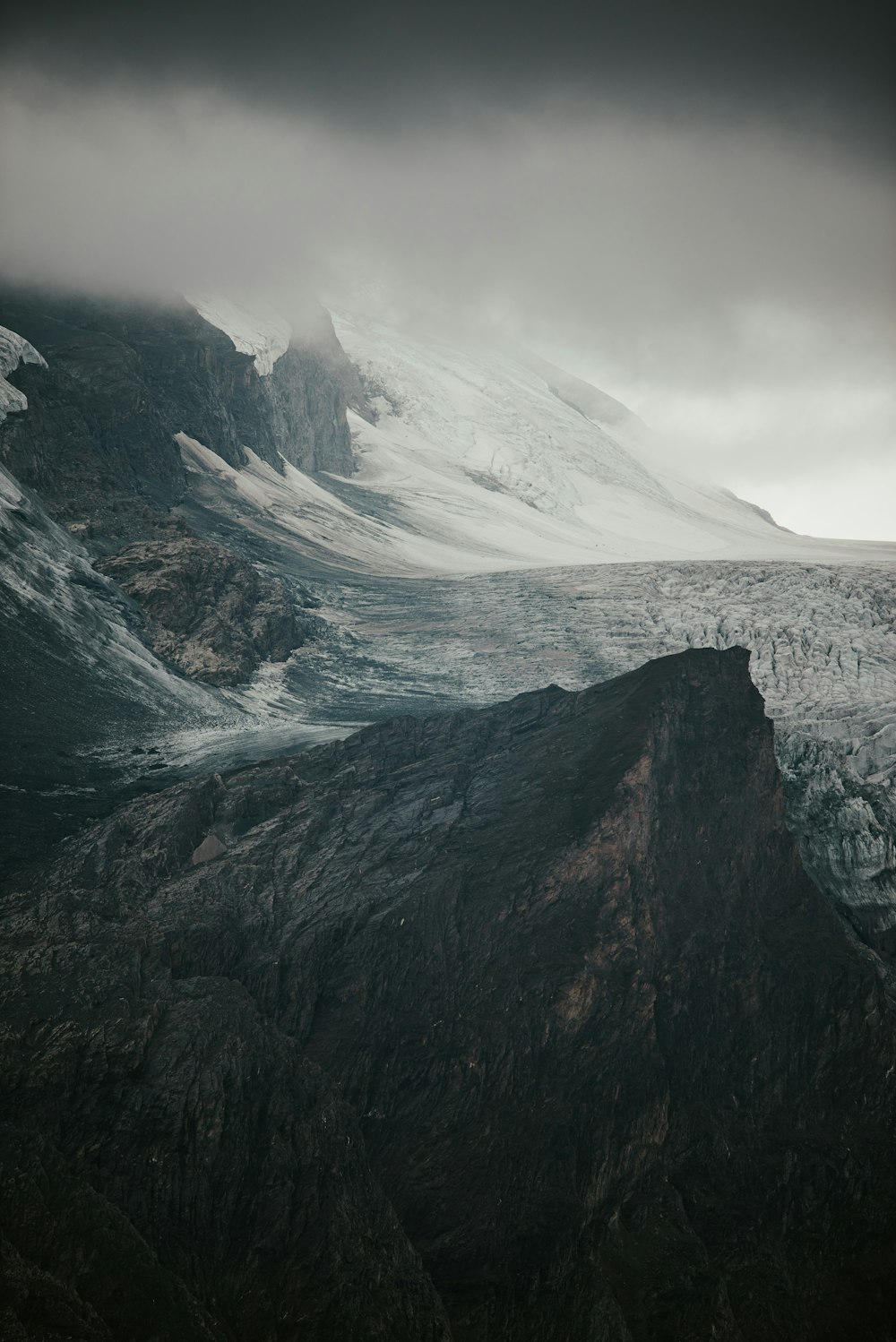 a mountain covered in snow under a cloudy sky