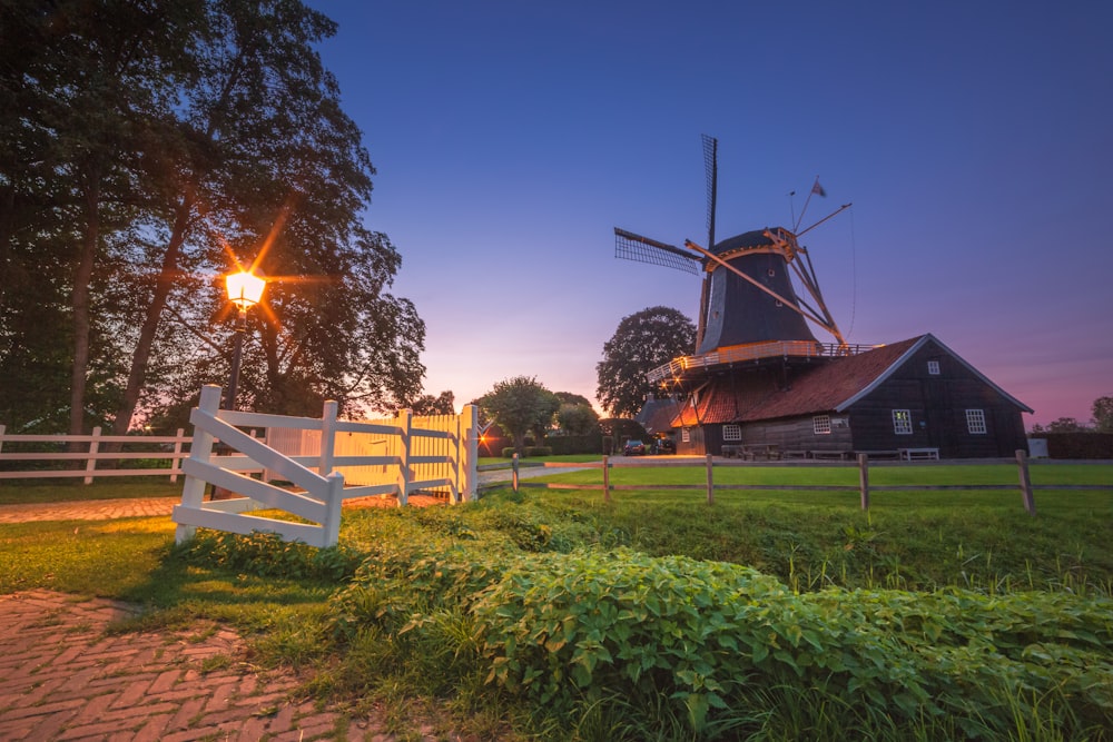 a windmill and a white fence in a field