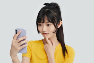 a woman in a yellow shirt holding a cell phone