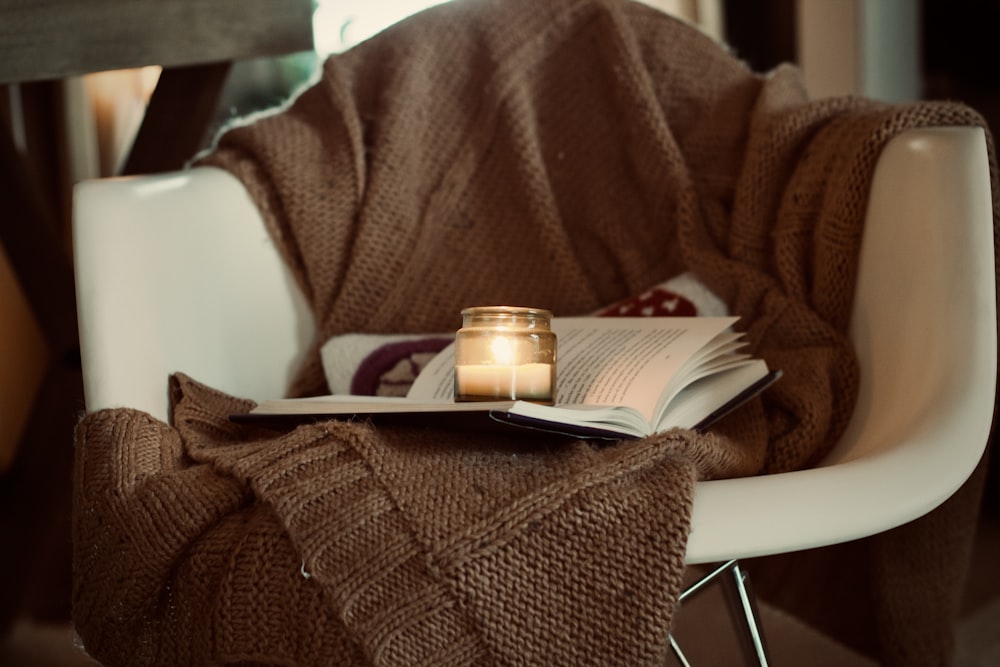 eine Kerze und ein Buch auf einem Stuhl