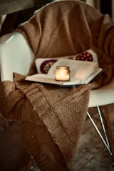 A plush warm blanket draped over a chair near a softly glowing fireplace