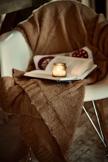 A cozy cardigan draped over a rustic wooden chair in a warm, inviting setting.