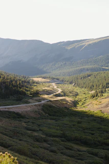 A winding mountain road cutting through lush green hills under a clear blue sky