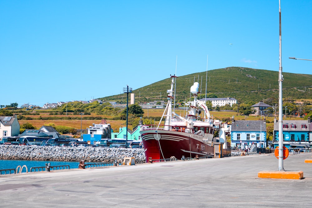 a boat docked in a harbor next to a hill