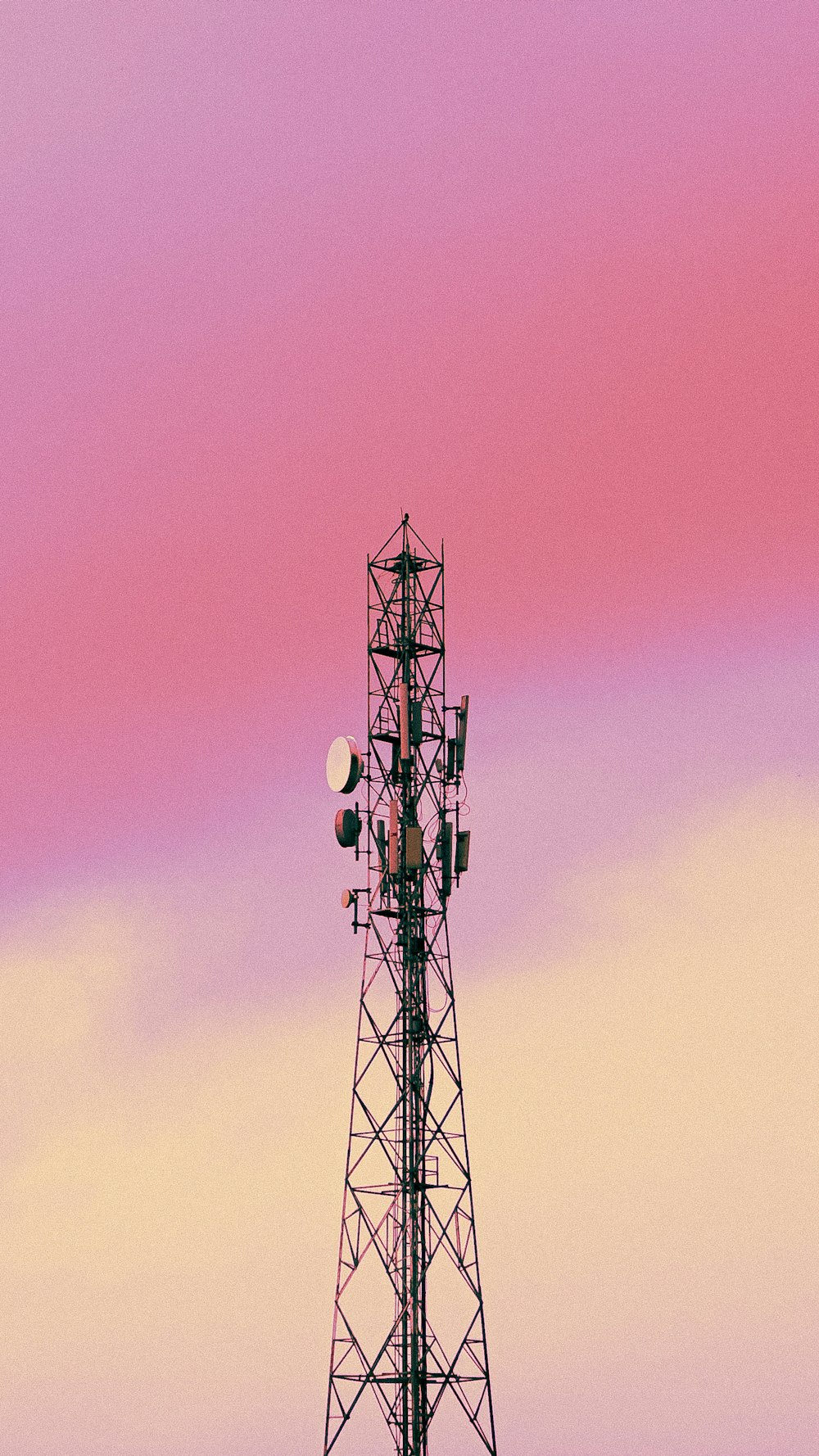 a cell phone tower with a pink sky in the background
