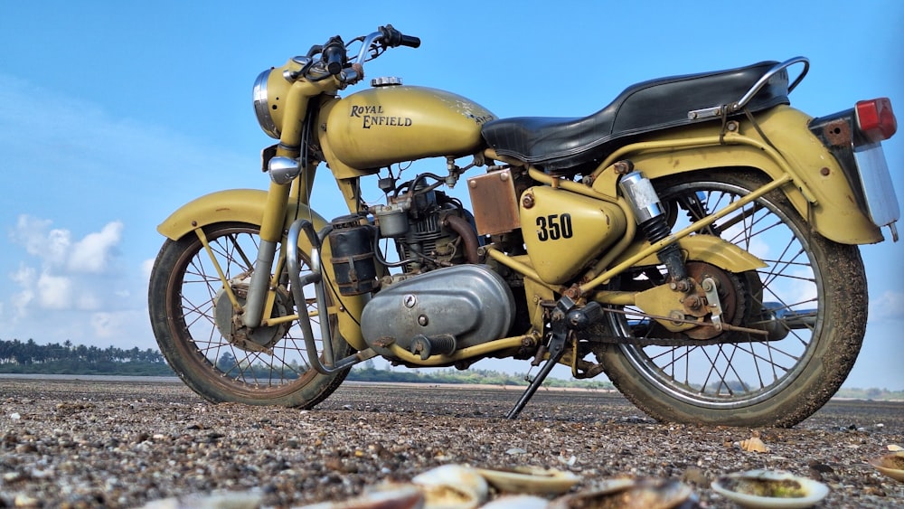 a yellow motorcycle parked on top of a sandy beach