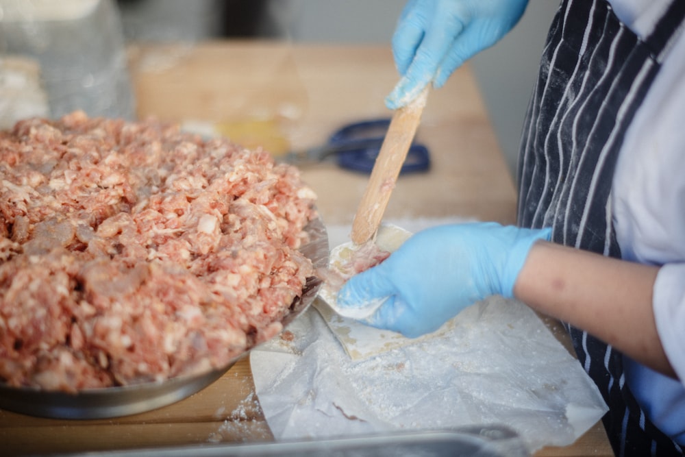 a person in blue gloves and gloves preparing food