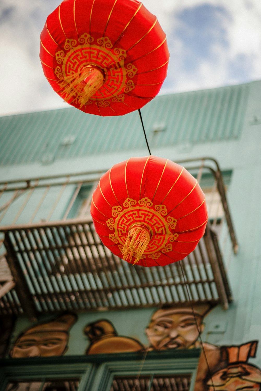 two red paper lanterns hanging from a blue building