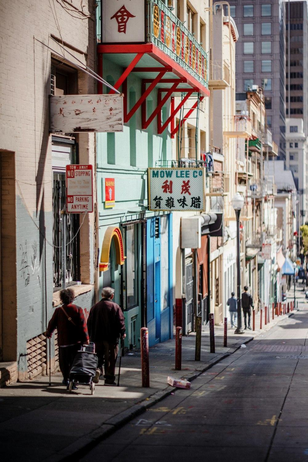 a couple of people walking down a street next to tall buildings