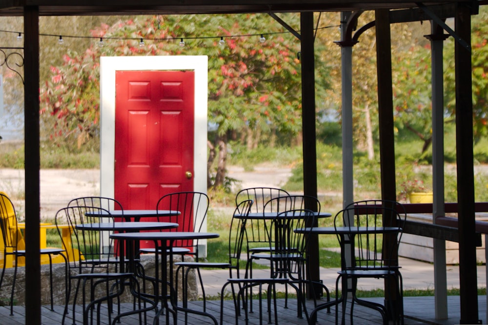 Une porte rouge se trouve à l’arrière-plan des tables et des chaises
