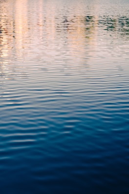 Gentle ripples on a quiet lake reflecting the pastel colors of early morning light.