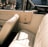 A vintage car interior featuring beige leather seats and a classic design. The upholstery is in pristine condition, evoking a sense of elegance and nostalgia. Sunlight streams through the windows, casting warm shadows.