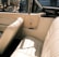 A vintage car interior featuring beige leather seats and a classic design. The upholstery is in pristine condition, evoking a sense of elegance and nostalgia. Sunlight streams through the windows, casting warm shadows.