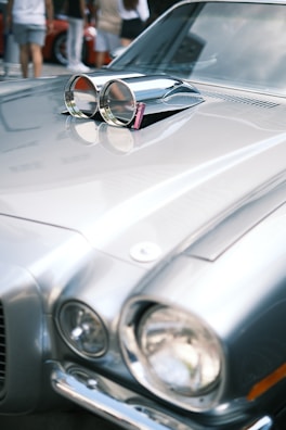 Close-up of a classic car’s polished hood reflecting the auction crowd.