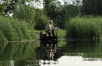 a man sitting on a dock fishing on a lake