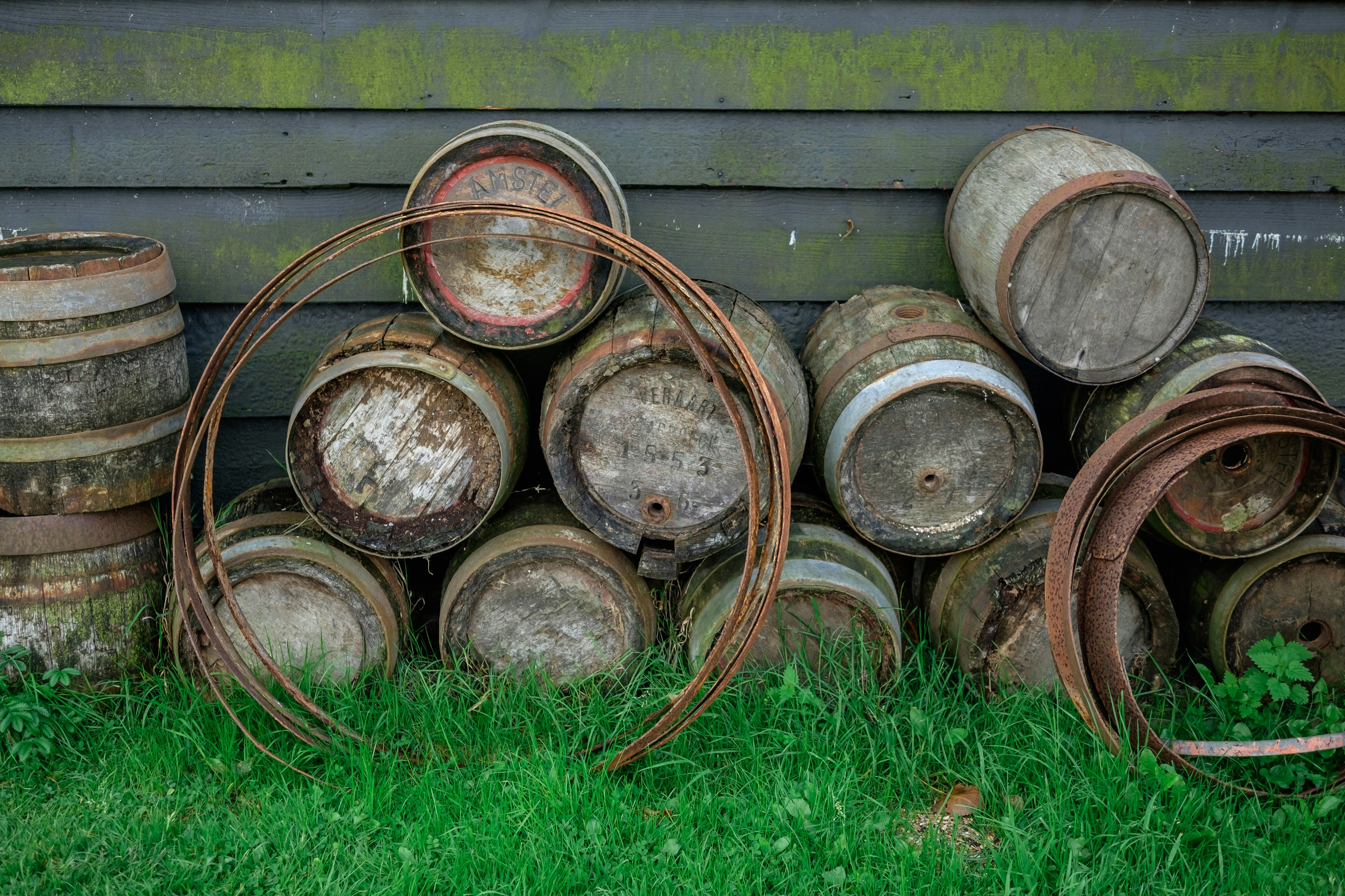 a pile of rusty barrels sitting on top of a lush green field