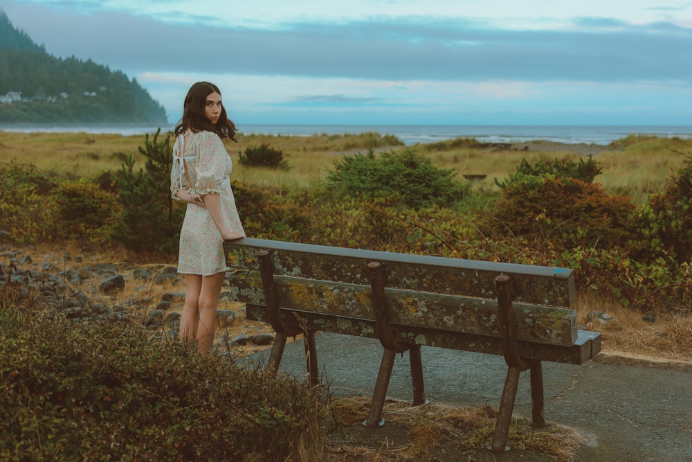 a woman standing next to a wooden bench