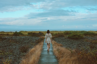 a woman in a white dress walking down a path