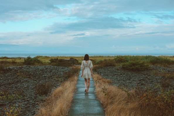 a woman in a white dress walking down a path