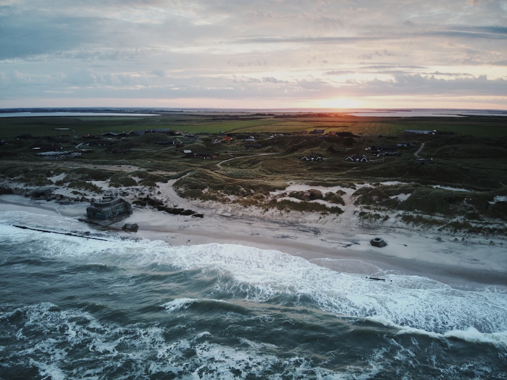 an aerial view of a beach and ocean at sunset