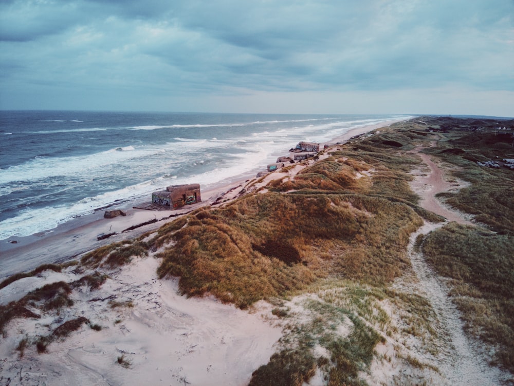 a sandy beach next to the ocean under a cloudy sky