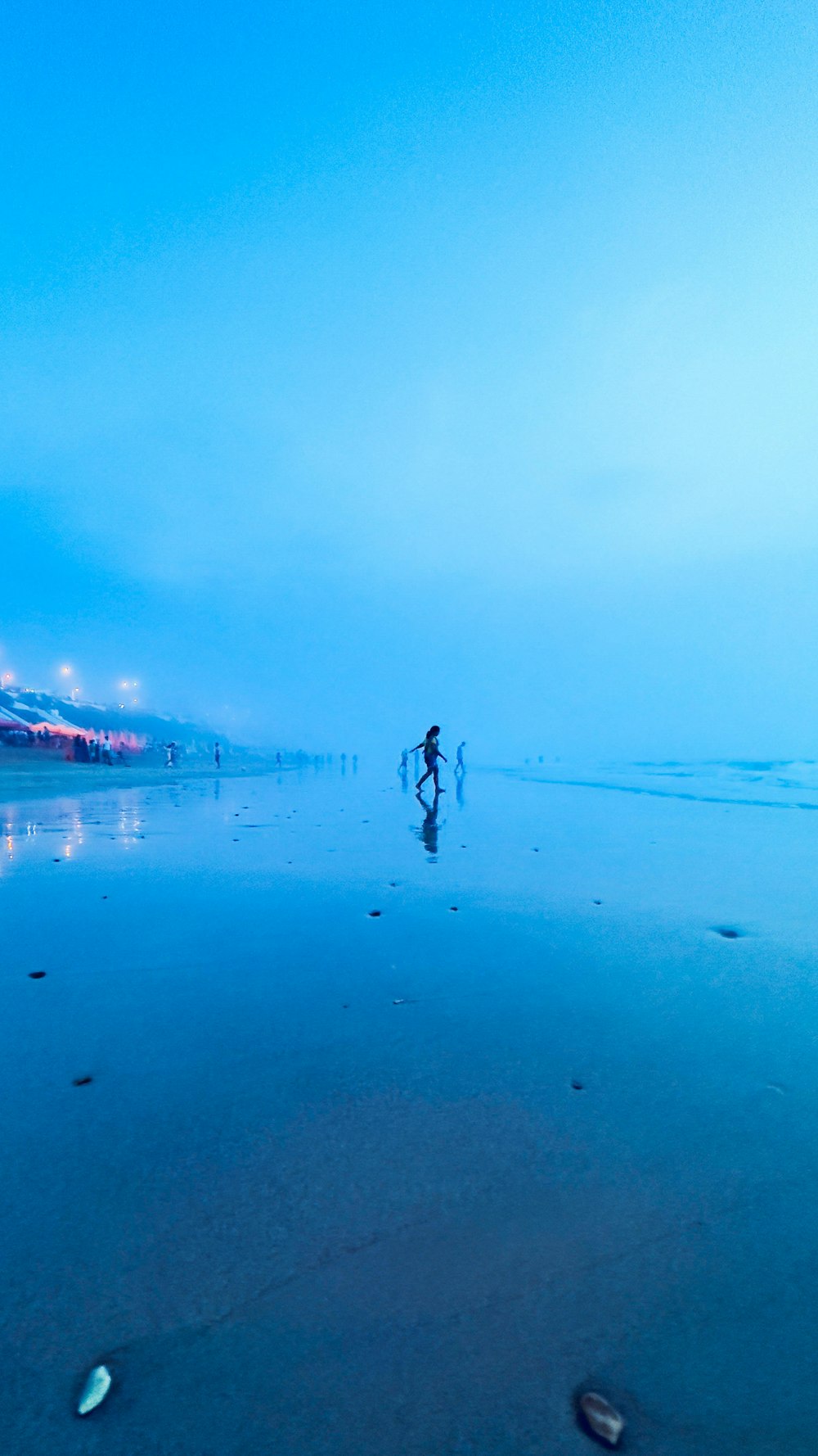 a couple of people walking across a wet beach