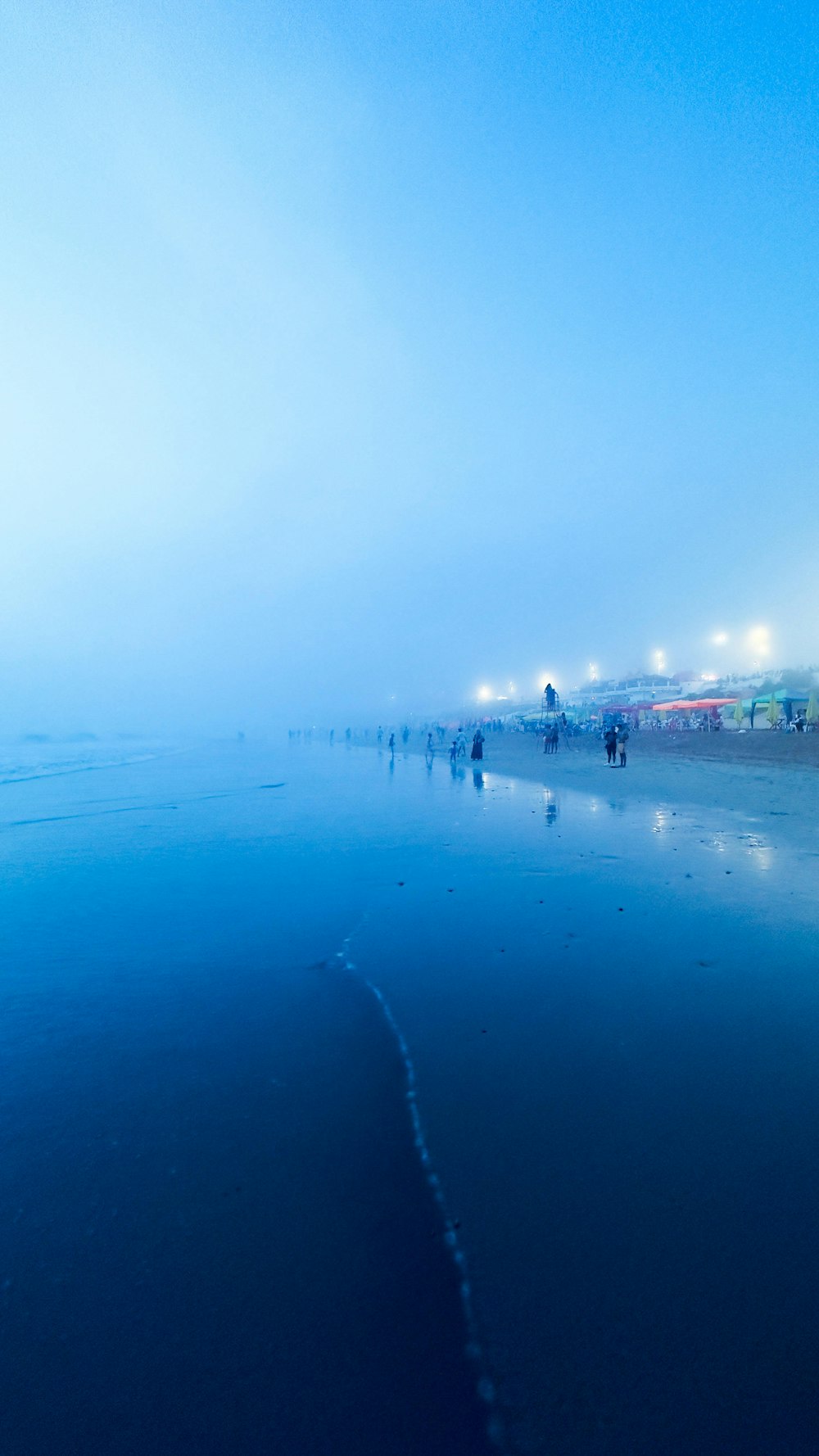 a group of people walking along a beach covered in fog