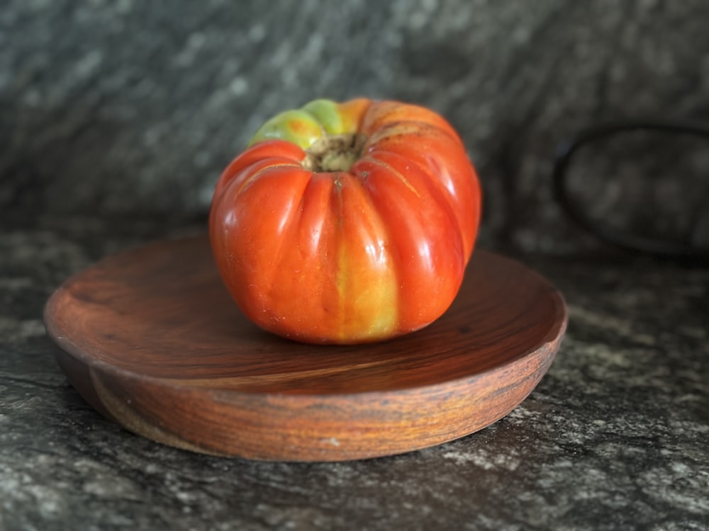 a small orange pumpkin sitting on top of a wooden plate