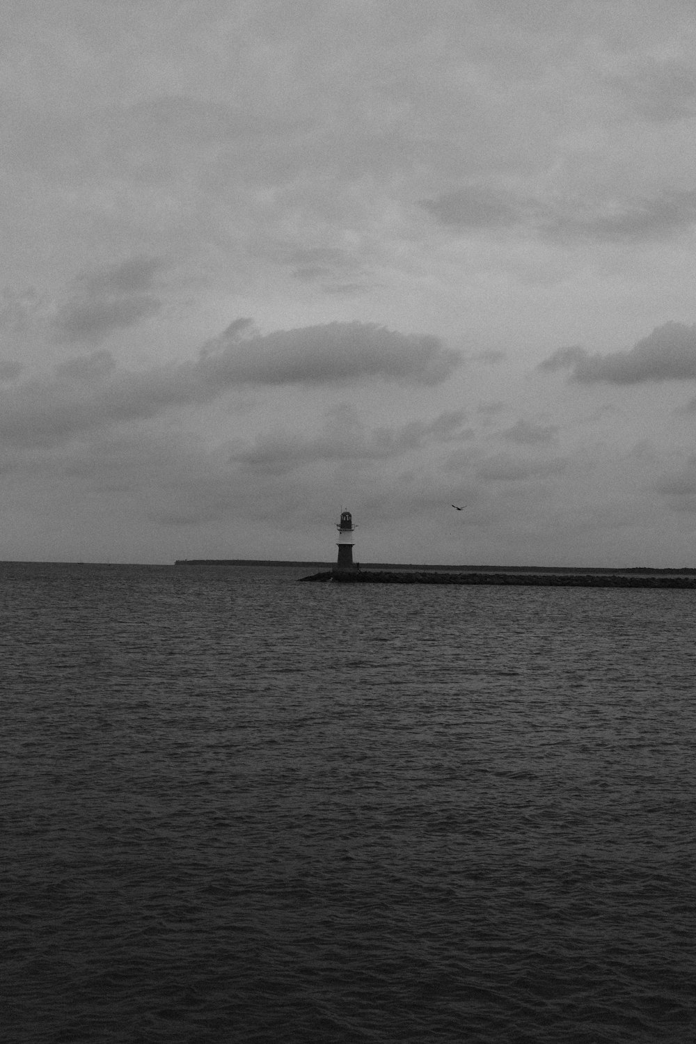 a black and white photo of a lighthouse in the middle of the ocean