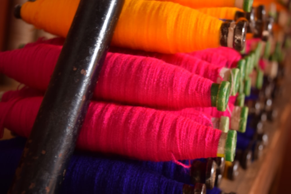 a row of colorful thread spools sitting on top of a wooden shelf