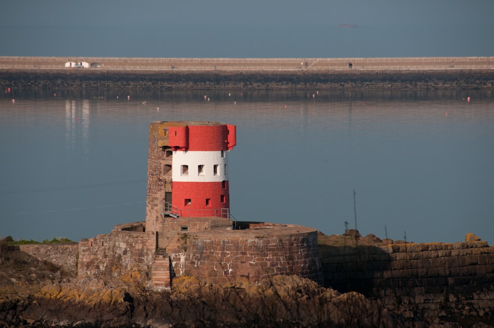 a red and white lighthouse sitting on top of a rock