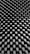 A close-up of a textured surface with a repeating pattern of peaks and valleys, resembling an acoustic foam panel. The surface has a monochrome appearance, showcasing a play of light and shadow across the geometric shapes.