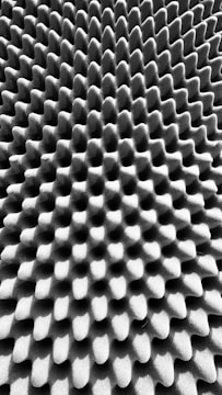 A textured surface with an intricate pattern of uniform, raised bumps and grooves, creating a three-dimensional effect.