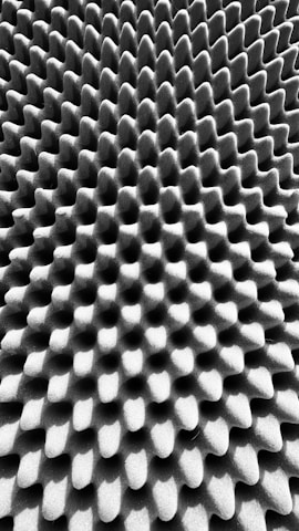 A textured surface with an intricate pattern of uniform, raised bumps and grooves, creating a three-dimensional effect.