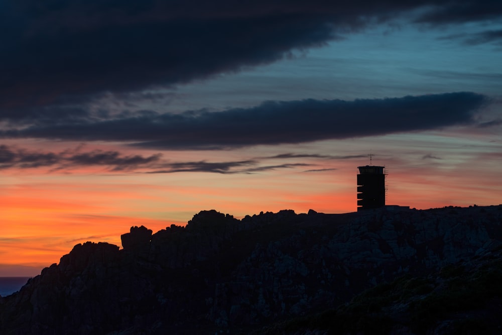 a tower on top of a mountain with a sunset in the background