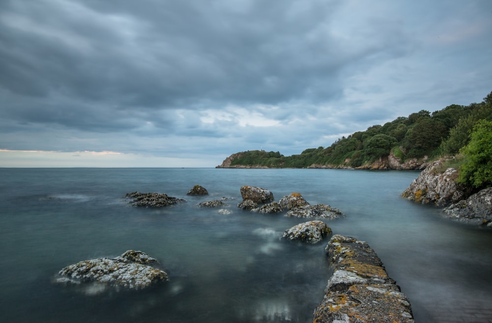 a body of water surrounded by rocks under a cloudy sky