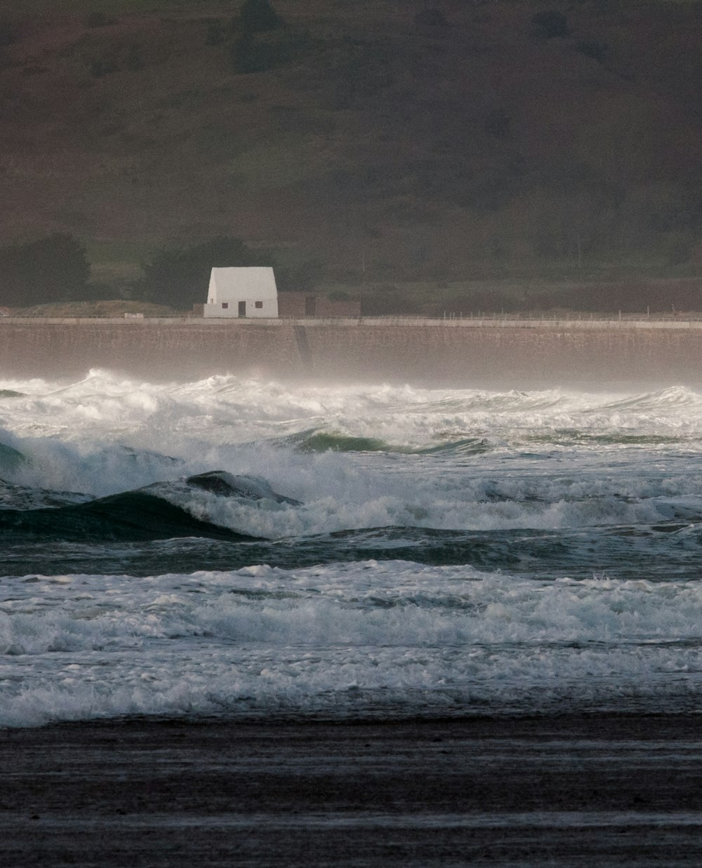 a white house sitting on top of a beach next to the ocean