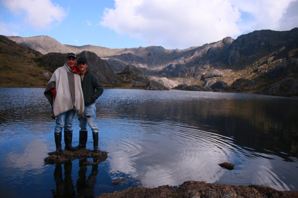 a couple of people standing in front of a body of water