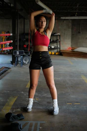 Athlete wearing sleek black and red gym wear stretching before workout in a modern gym