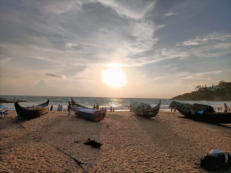 A serene Balinese beach at sunset with traditional fishing boats resting on the shore.